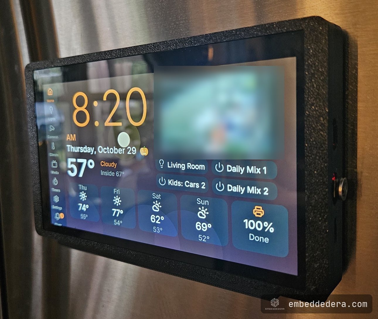The panel on the fridge seen from the side, showing the slim printed case, the cradle underneath and the USB-C ports and switch on the right edge.